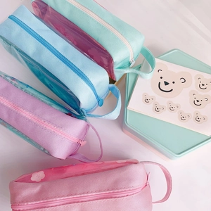Detail of large transparent pencil cases in pastel colors with side handle and zipper