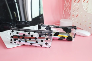 Detail view of transparent PVC pencil cases with black polka dots and cloud patterns