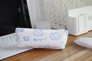 Detailed view of a white canvas pencil case with cute rabbit illustrations on a desk