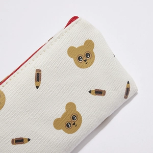 Close-up of white canvas pencil case with bear patterns and red zipper detail