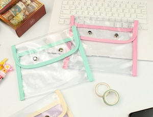 Close-up of clear PVC stationery pouches with colorful fabric edges and metal snap buttons