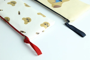 Detail of two canvas pencil cases with cartoon bear prints and colorful zipper closures