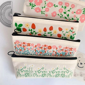 Detail of four floral canvas pencil cases featuring strawberry and daisy prints for students