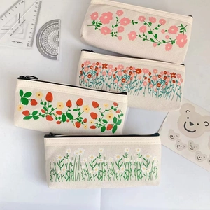 Flat lay of multiple canvas pencil cases with floral and strawberry prints and black zippers
