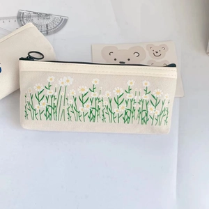 Detail of cream canvas pencil case with embroidered small white flowers and green grass pattern