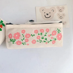 Close-up of a cream canvas pencil case featuring pink floral patterns and a metal zipper