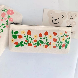 Detail of cute canvas pencil case showing strawberry floral prints and black zipper closure