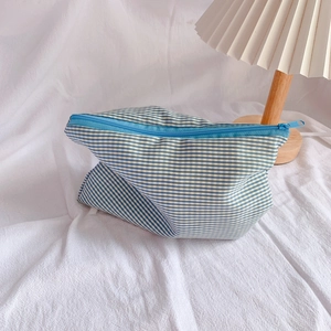 Close-up of blue and white checkered fabric pencil case with a zipper on a white fabric