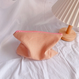 Detail of checkered pencil case with pink zipper on a warm aesthetic background