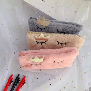 Detailed view of plush pencil cases in pink, grey and beige with gold crown embroidery