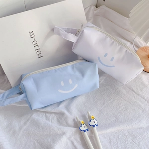 Detail of minimalist canvas pencil cases with smiling face print and side carry strap