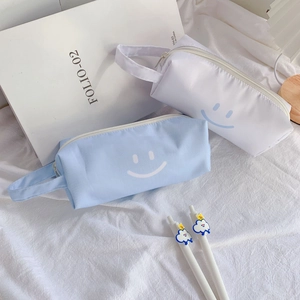 Detail of canvas pencil cases with smiley face, blue cloud and star pens on fabric