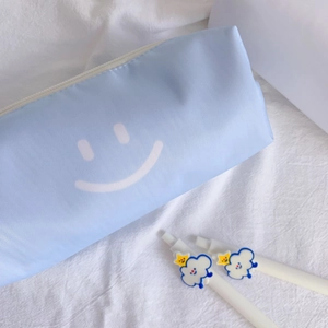 Close-up of light blue pencil case with smiley face pattern and two cartoon cloud pens