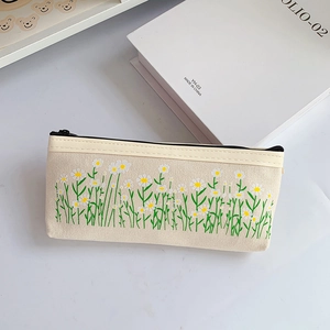 Close-up of canvas pencil case featuring white daisy patterns and black zipper closure