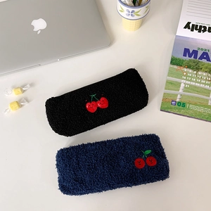 Macro detail of plush cherry embroidery on lamb wool pencil cases in navy and black