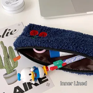 Navy blue plush cherry pencil case with lining and embroidery on white desktop