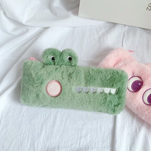 Close-up of a green plush crocodile pencil case with embroidery details and soft texture