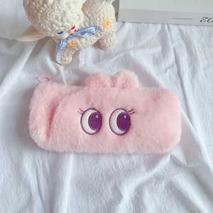 Detail showing soft pink plush pencil case with cute embroidered eyes and rabbit ears