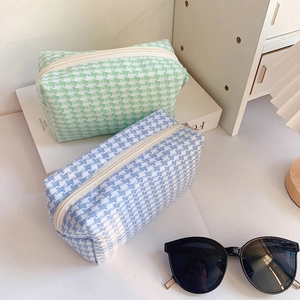 Close-up of pastel houndstooth makeup bags with white zipper detail in light blue and green