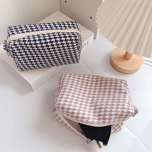Macro view of houndstooth makeup bags in black and brown with metal zippers