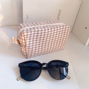 Close-up of houndstooth makeup bag and stylish oversized sunglasses on display