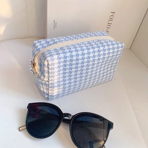 Detailed view of light blue houndstooth makeup bag with white zipper and gold puller