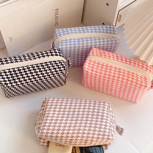 Macro detail of houndstooth fabric makeup bags in various candy colors with zip closures