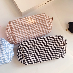 Detail view of woven houndstooth cosmetic bags in blue and brown with metal zippers