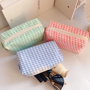 Macro view of woven houndstooth cosmetic bags with zipper closure and internal storage space