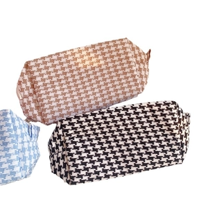 Three houndstooth pattern toiletry bags in light blue, khaki, and black white colors
