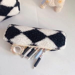 Close-up of fluffy black and white checkered pencil case with stationery inside