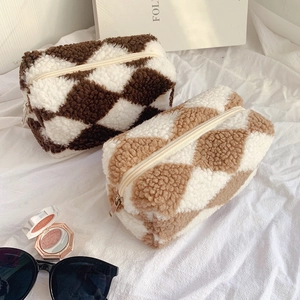 Detail of plush checkerboard pouches with soft faux fur texture and sturdy metal zipper