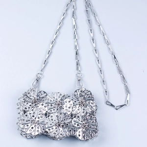 Macro detail of silver metal petal sequins and geometric chain on handcrafted crossbody bag