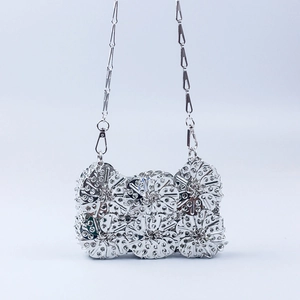Detail of silver metallic flower-shaped chain bag with kitten silhouette and polished finish