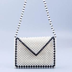 Detail of handcrafted pearl envelope bag with black and white woven beads and strap