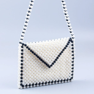 Detail of handmade faux pearl envelope bag with black and white woven beaded pattern