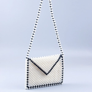 Detail of handmade beaded envelope bag with ivory pearls and black trim accents