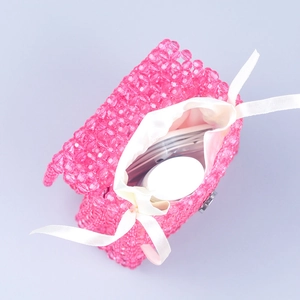 Detail view of pink beaded handbag interior with satin drawstring pouch and storage capacity