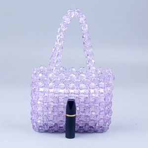 Détail d'un mini sac à main en perles mauves avec rouge à lèvres pour taille