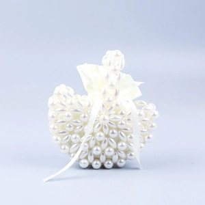 Detail of beaded pearl handbag featuring a white satin drawstring pouch and ribbon bow