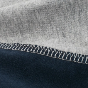 Close-up of grey and navy blue patchwork fabric with fine white stitching on a boy's t-shirt
