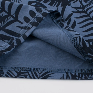 Close-up of boys blue-grey cotton T-shirt showing hem stitching and tropical leaf print