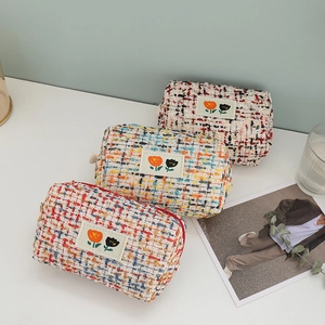 Close-up of tweed cosmetic bags with tulip embroidery and durable zipper closure