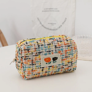 Close-up of tweed makeup bag fabric texture with tulip patch and yellow zipper
