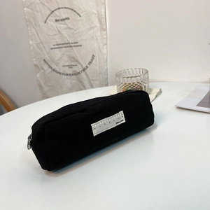Detail view of black canvas pencil case with a unique ruler label and metal zipper