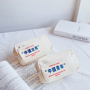 Close-up of cream canvas pencil cases with front pockets and slogan prints