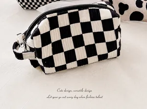 Close-up of small black and white checkered makeup bag with ripple texture and handle
