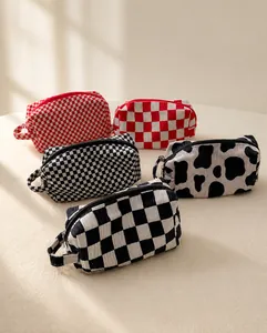 Detailed view of checkered and cow print cotton cosmetic bags with black zippers