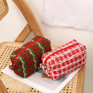 Close-up of red and green knitted makeup bags with metal zippers on a rustic chair