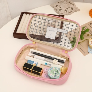 Pink multi-functional pencil case with black mesh flap lid on white desk surface
